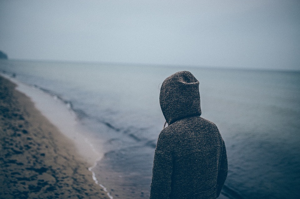 Woman wearing hoodie walking on beach