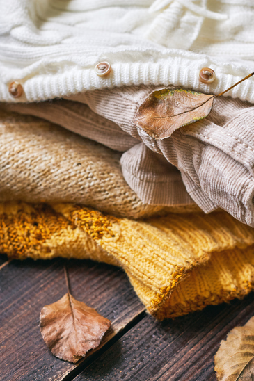 Stack of fall clothes for women on wooden background