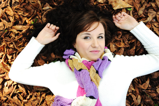 Young beauty girl laying on autumn ground and leaves, perfect face and natural skin, fashionable fall clothes