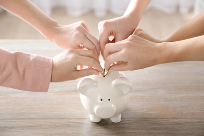 hands putting coins in piggy bank