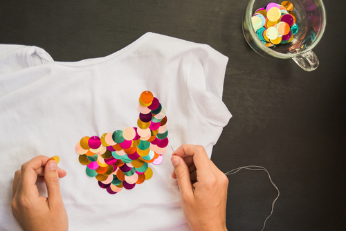 person decorates blank t-shirt sequins