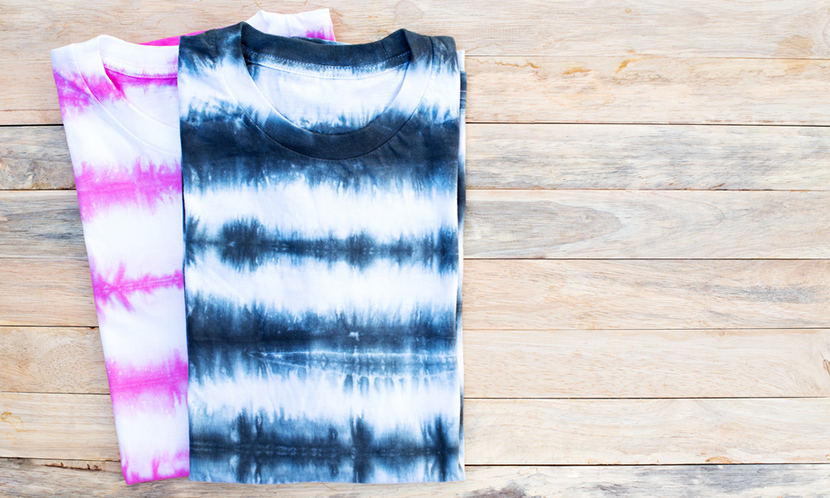 two tie dyed shirts folded wooden desk