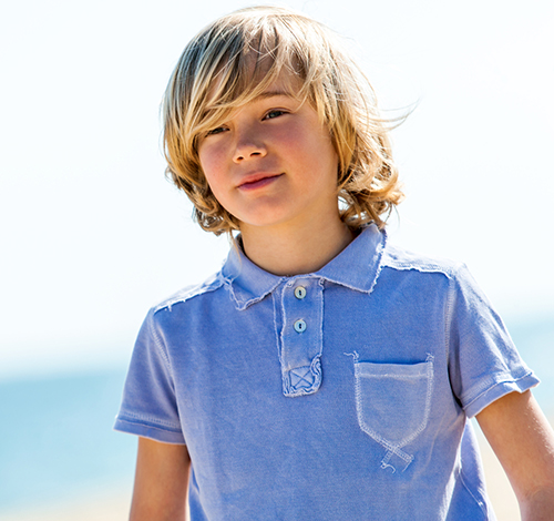 portrait of boy wearing worn polo shirt outdoors