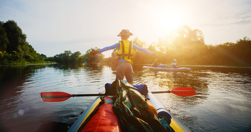 boy standing on kayak in lake