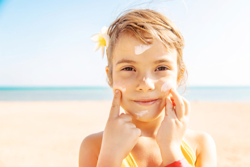 child putting sunscreen on face