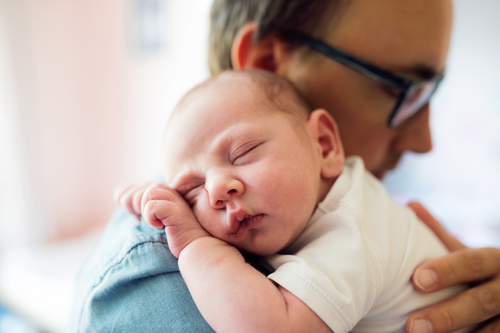 father holding newborn baby on shoulder