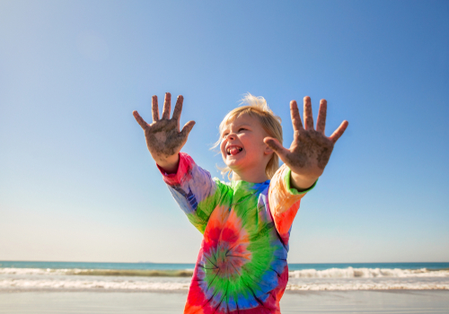 girl in tie dye shirt having fun at beach