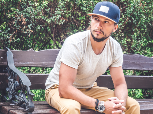 Man sitting on bench in gray t-shirt and Blue Baseball Cap