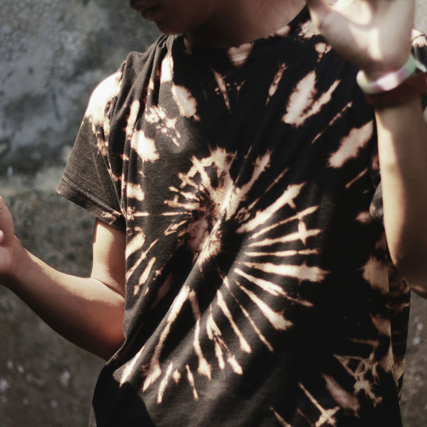 a man wearing a spiral pattern black and yellow reverse tie dye shirt