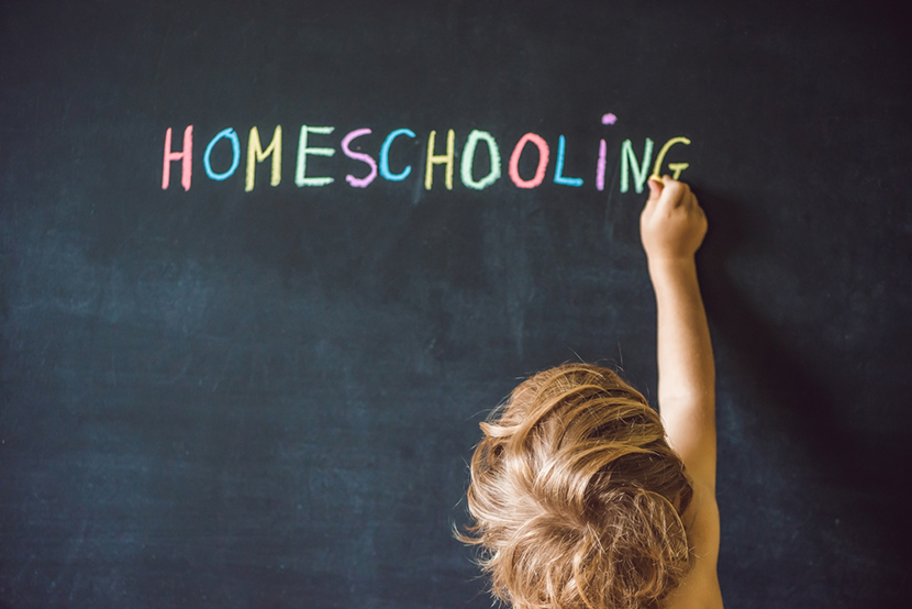 a child writing homeschooling on a black board