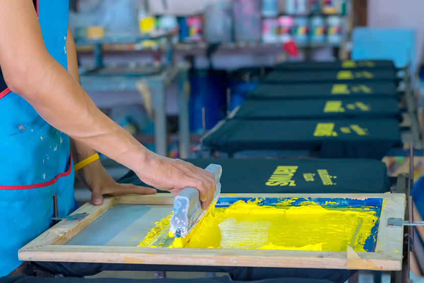 a person screen printing on t shirts in yellow