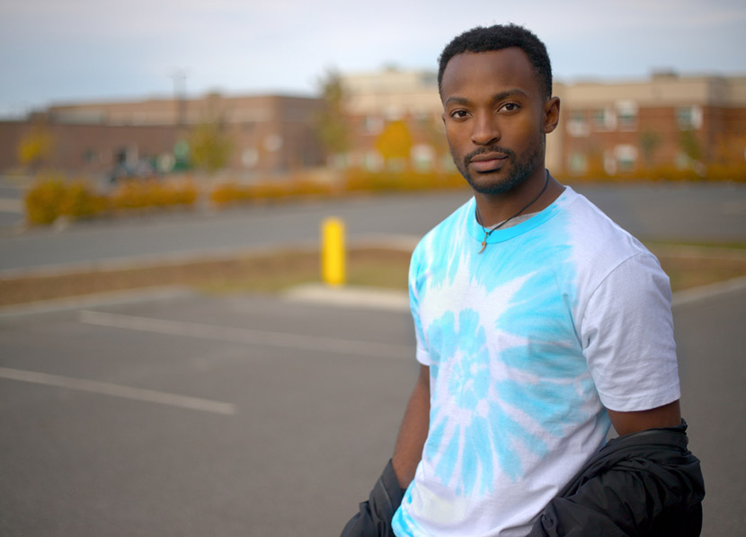 young african man wearing tie and dye pastel t-shirt psychedelic pattern fashion outside in the parking lot
